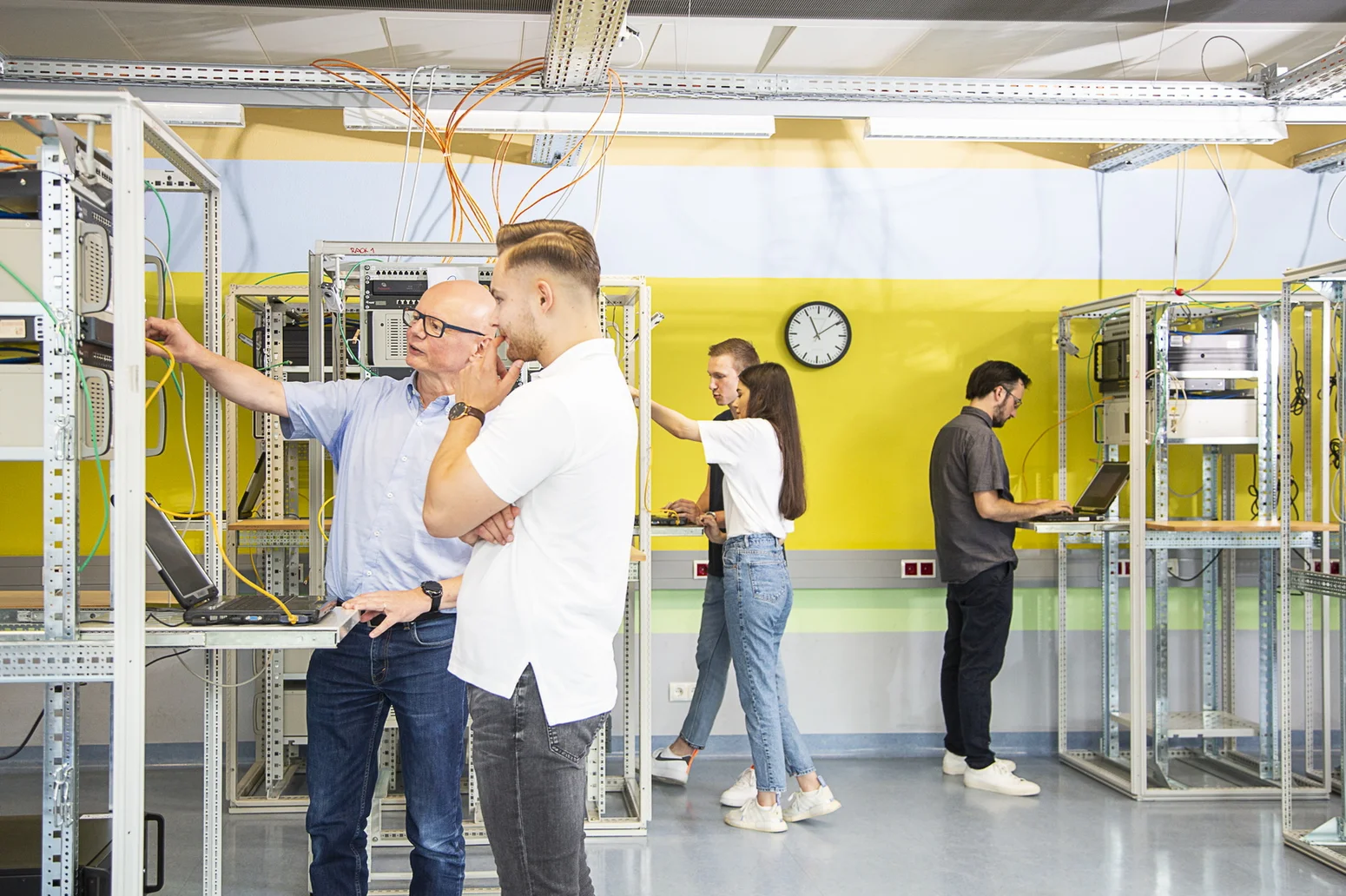 Studenten arbeiten im Netzwerkraum mit Professor 