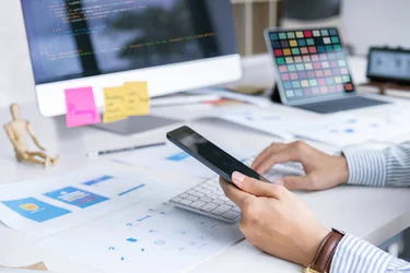 Person entwickelt eine mobile Anwendung mit Smartphone und Entwürfen für Benutzeroberflächen.