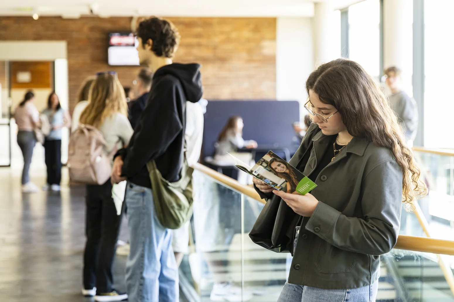 Studieninteressierte mit Flyer in der Hand.