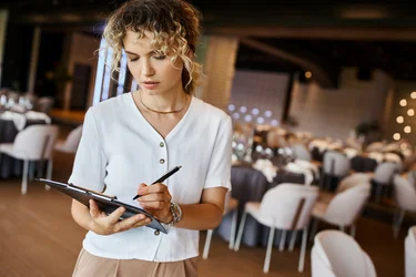 Eventmanagerin bearbeitet eine Checkliste in einem Bankettsaal