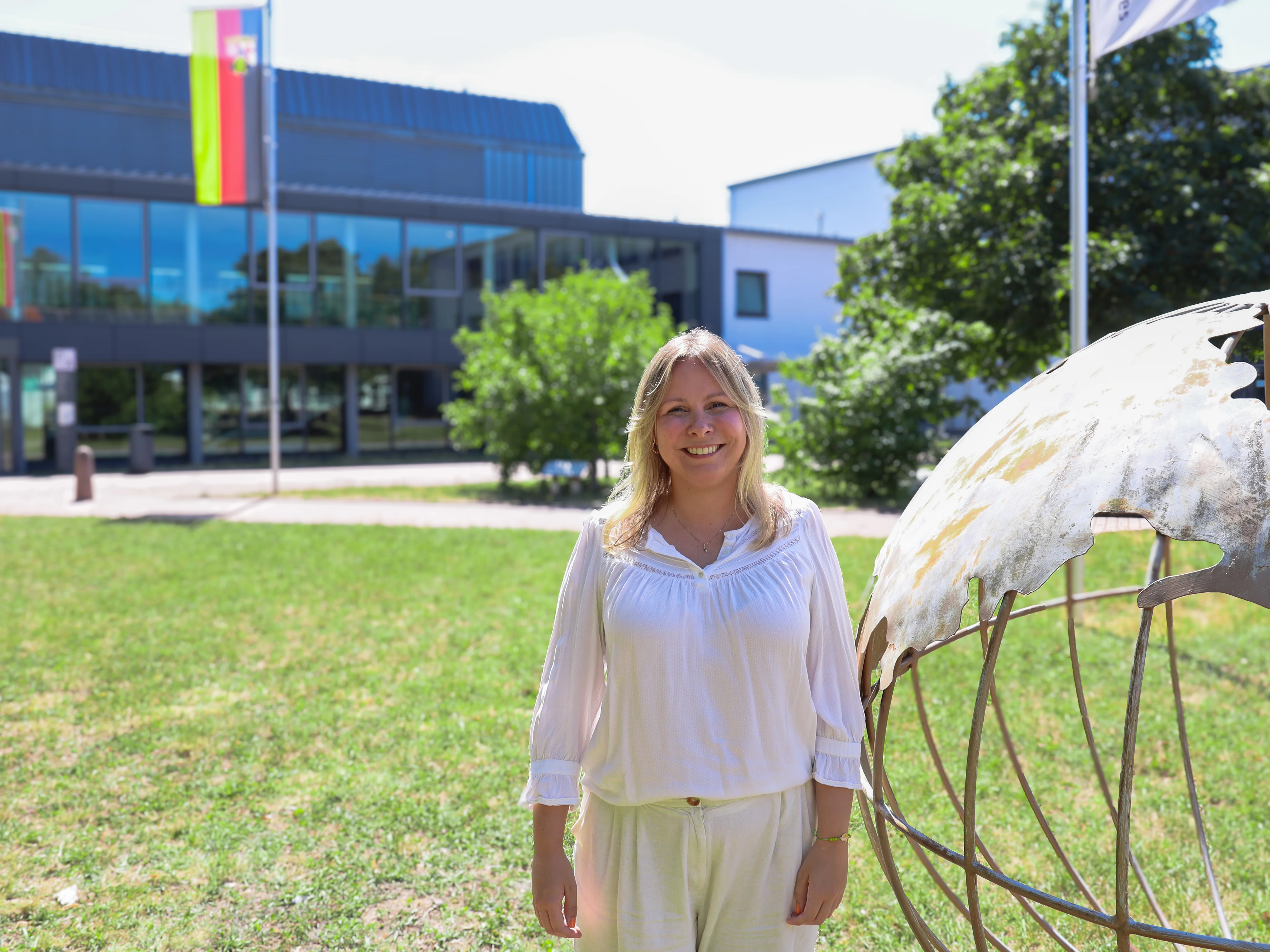 Die neue regionale Integrationsbeauftragte für die Hochschule Worms Christina Paul steht vor der Statue einer Weltkugel auf dem Campusgelände der Hochschule Worms.