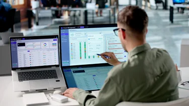 IT-Manager analysiert digitale Assets und Systemkennzahlen an mehreren Bildschirmen.
