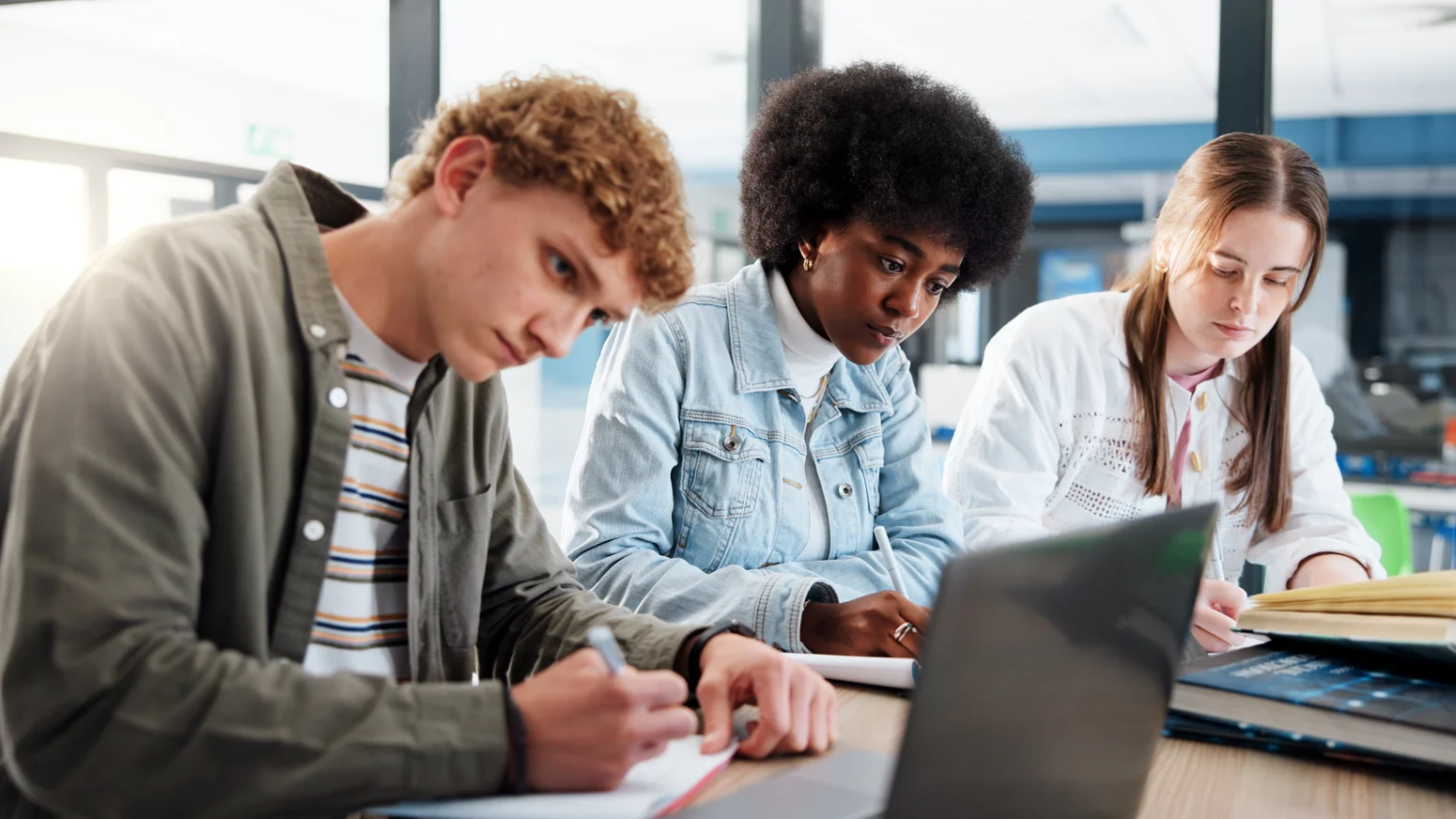 Eine Gruppe Studierender lernt gemeinsam in der Bibliothek der Hochschule Worms mit Laptop und Büchern.