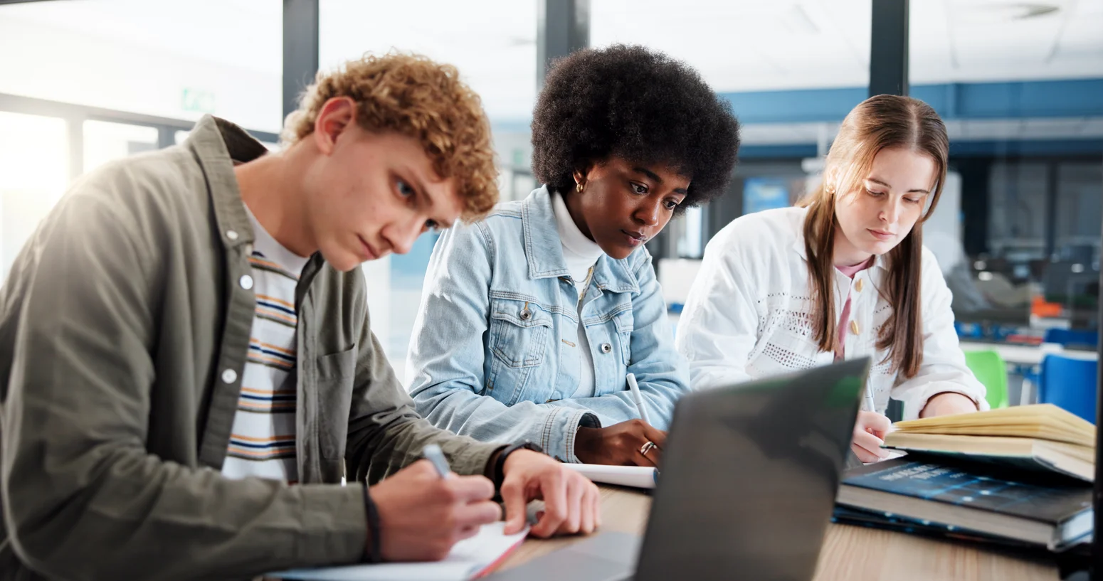 Eine Gruppe Studierender lernt gemeinsam in der Bibliothek der Hochschule Worms mit Laptop und Büchern.