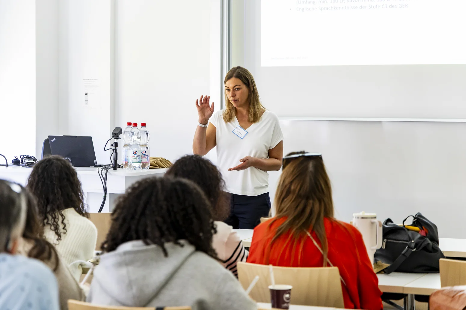 Eine Mitarbeiterin steht vor Studieninteressierten und hält einen Vortrag in einem Seminarraum der Hochschule Worms.