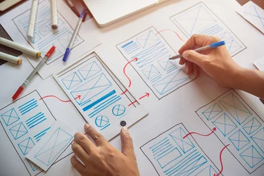 Skizzierte Wireframes für eine mobile Benutzeroberfläche werden auf Papier entworfen.