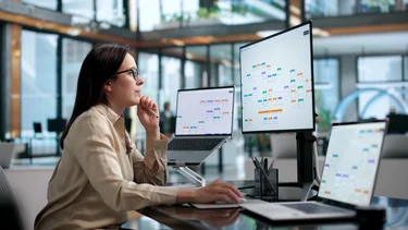 Frau analysiert digitale Workflow- und Prozessdarstellungen an mehreren Bildschirmen.